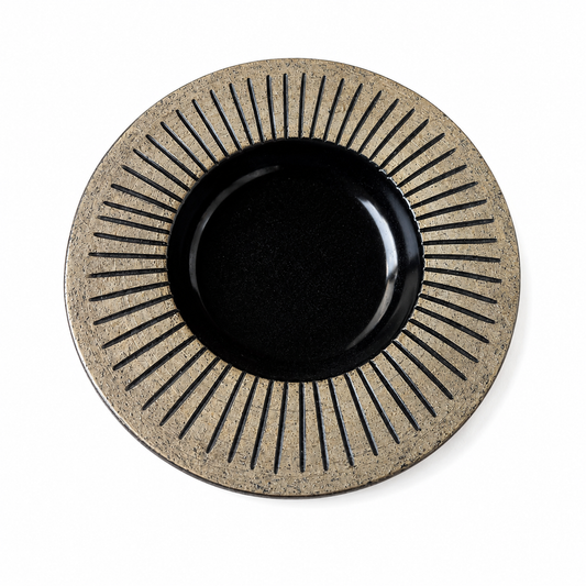 Dekorativt vintagefat i keramik från Gabriel Keramik med strålmönster i guld och beige runt blank svart mitt